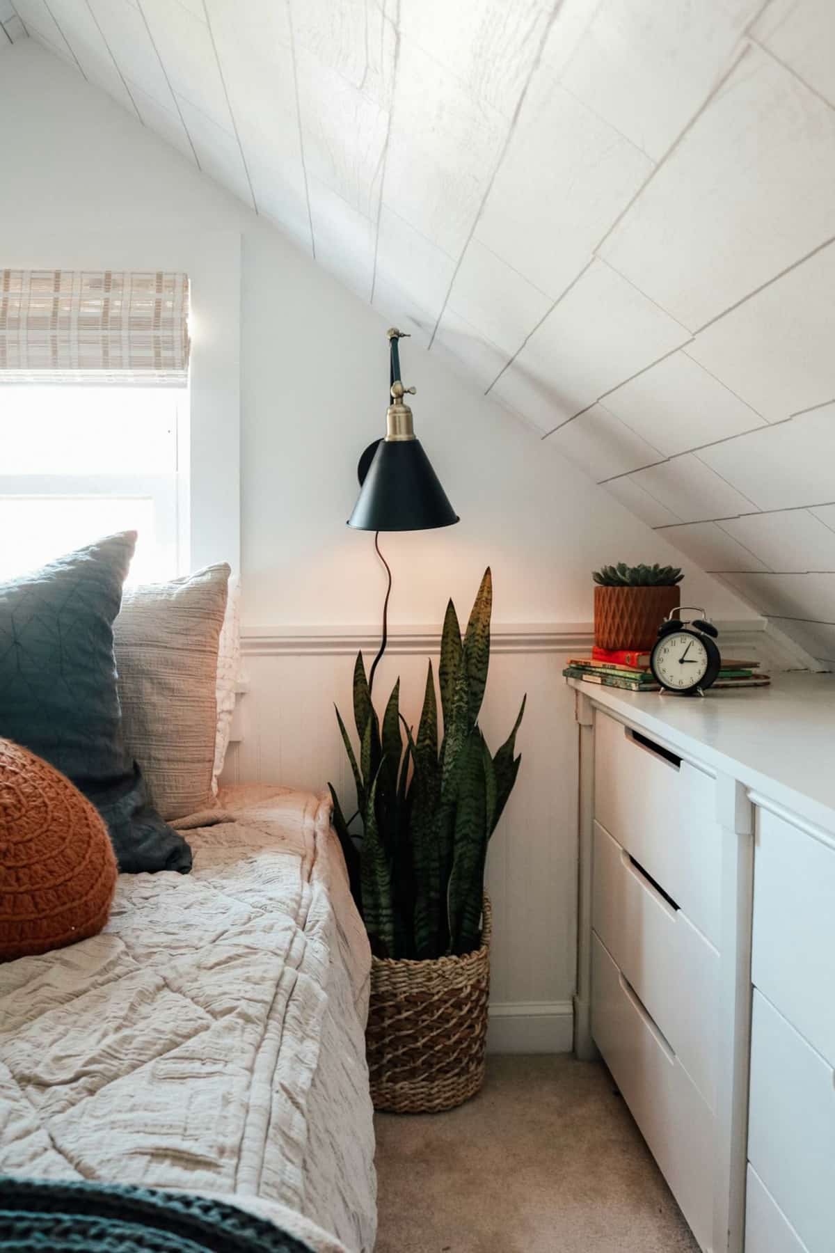 Light colored slanted wall bedroom with plants and sconces
