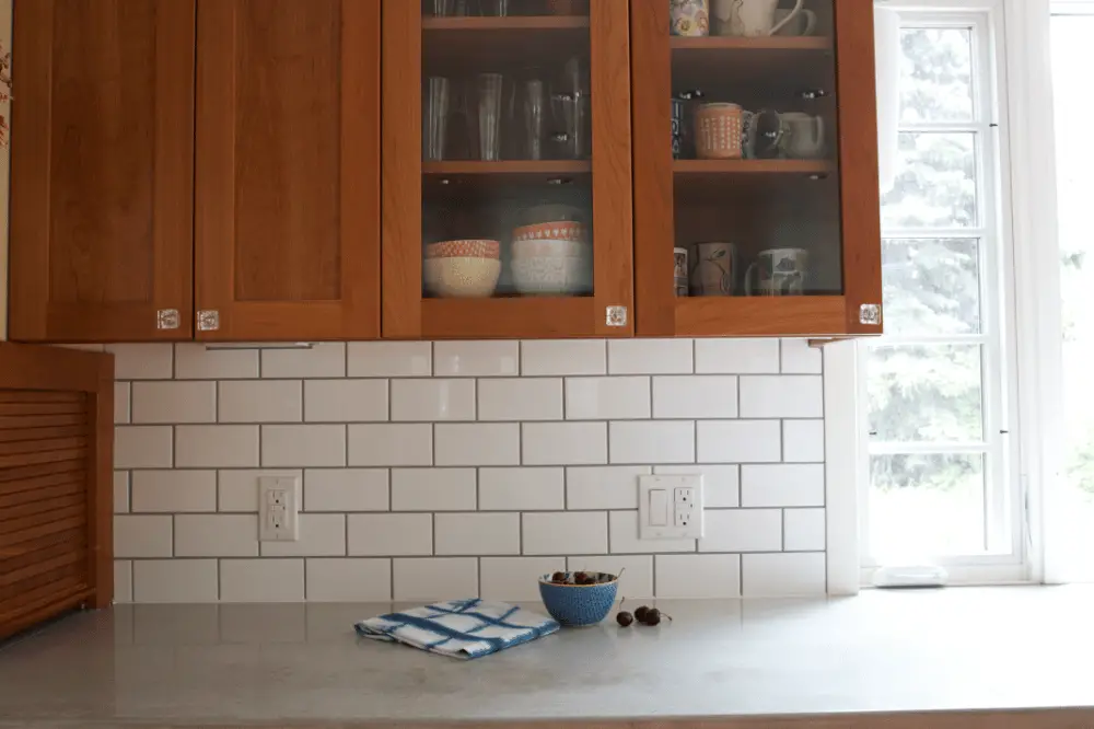 Install a backsplash in a light color to brighten the wood kitchen cabinets.