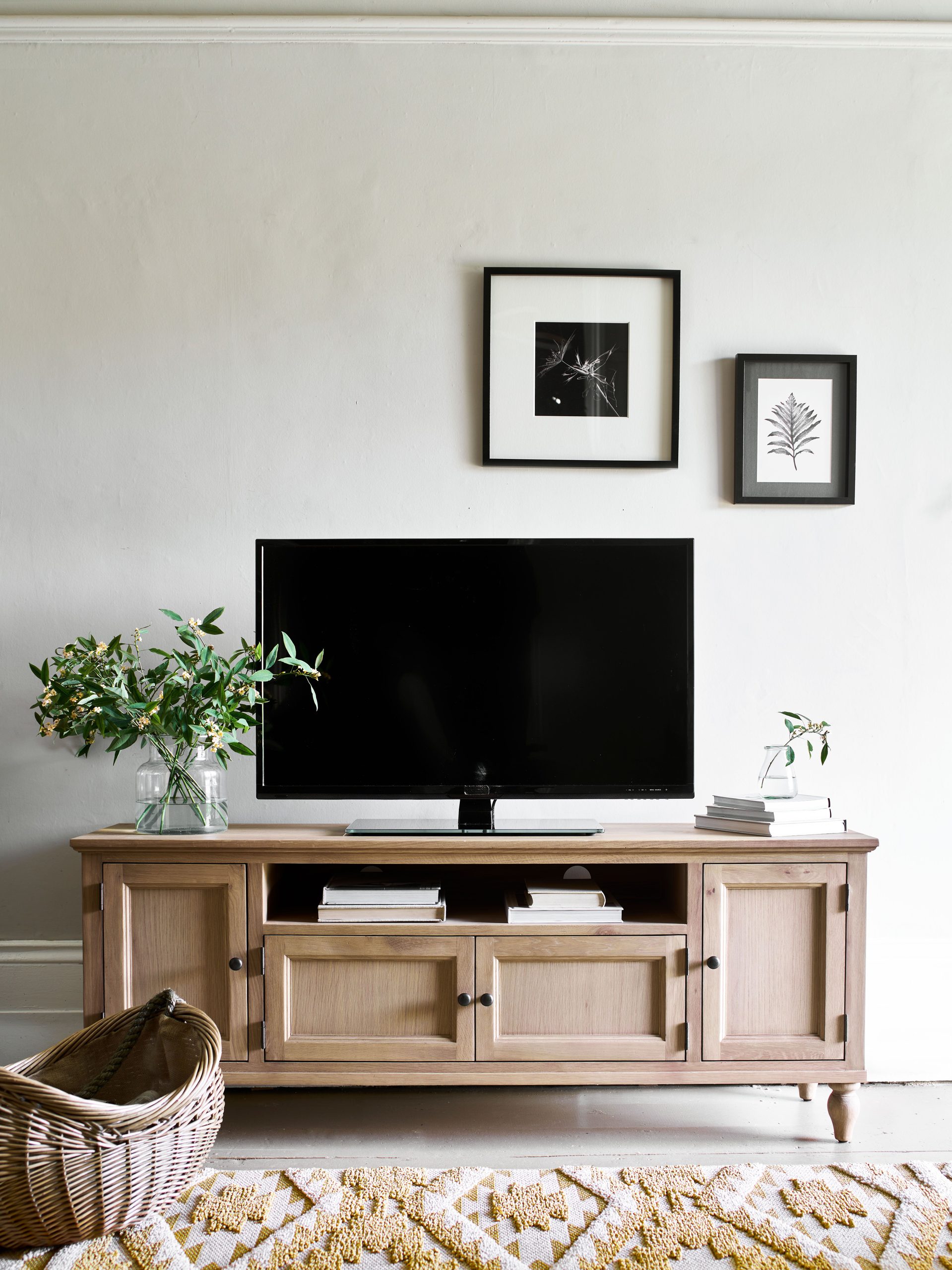 Utilize the wall space above and around the TV console, such as wall art, a mirror, or floating shelves, to help emphasize…