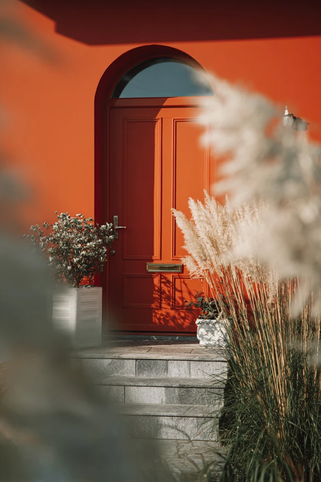 Terracotta-toned orange front door shown against the home's exterior wall